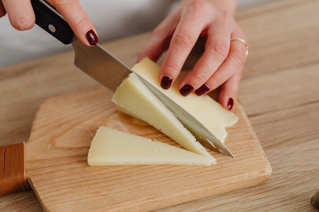 Hands slicing a wedge of Amish Country cheese on a wooden cutting board, Holmes County Ohio
