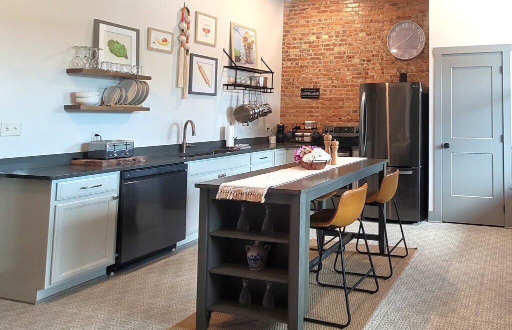 Art-filled kitchen with exposed brick and island seating at Suite on Jackson in Historic Downtown Millersburg