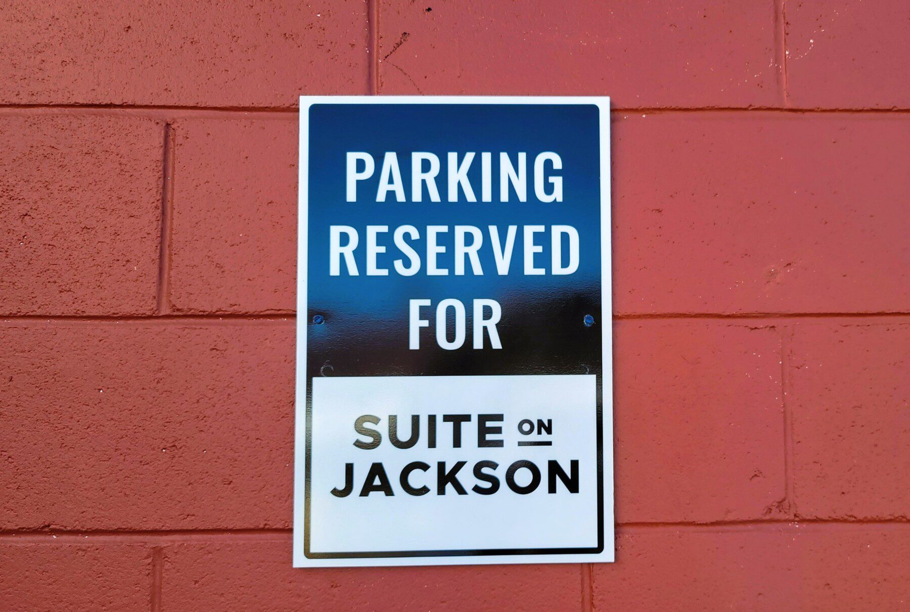 Reserved parking sign for Suite on Jackson mounted on a red brick wall