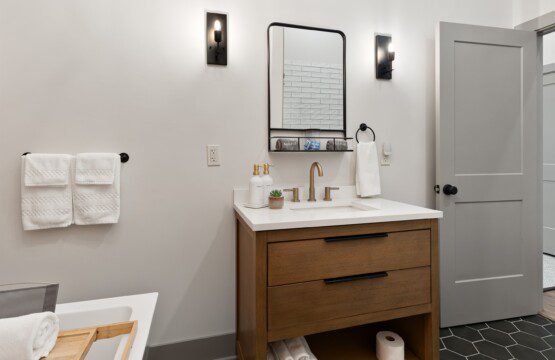Wood vanity with a white counter, framed mirror, and gold fixtures in the bathroom