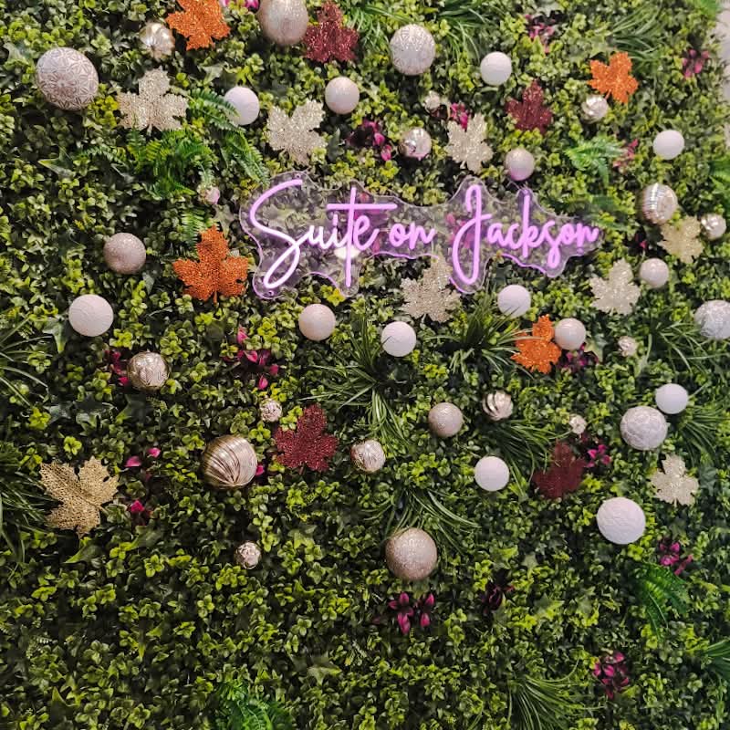 Suite on Jackson neon sign on a lush green foliage wall decorated with fall leaves at the boutique suite in Millersburg, Ohio