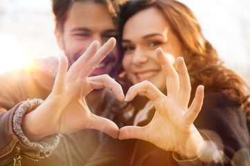 Couple making a heart with their hands at sunset on a romantic weekend getaway