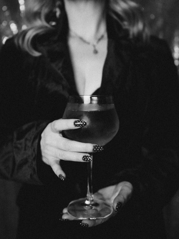 Woman holding wine glass with fresh manicured nails in a polka dot design